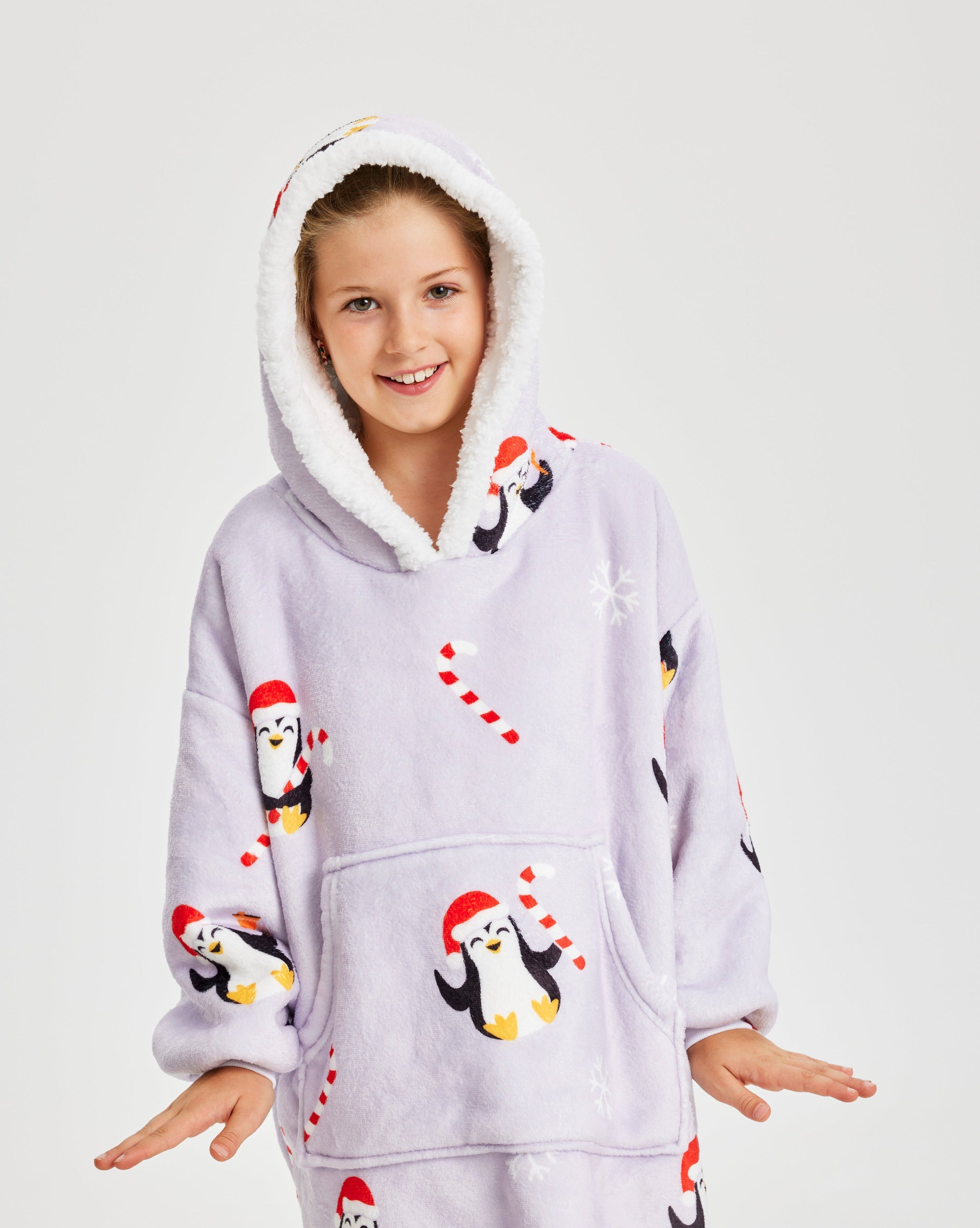 Een poserend kind dat een lichtpaarse kerst hoodie draagt met pinguïns erop.